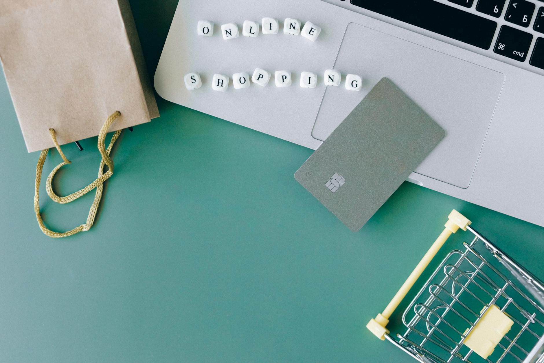 Laptop, karta płatnicza i mini wózek zakupowy na biurku