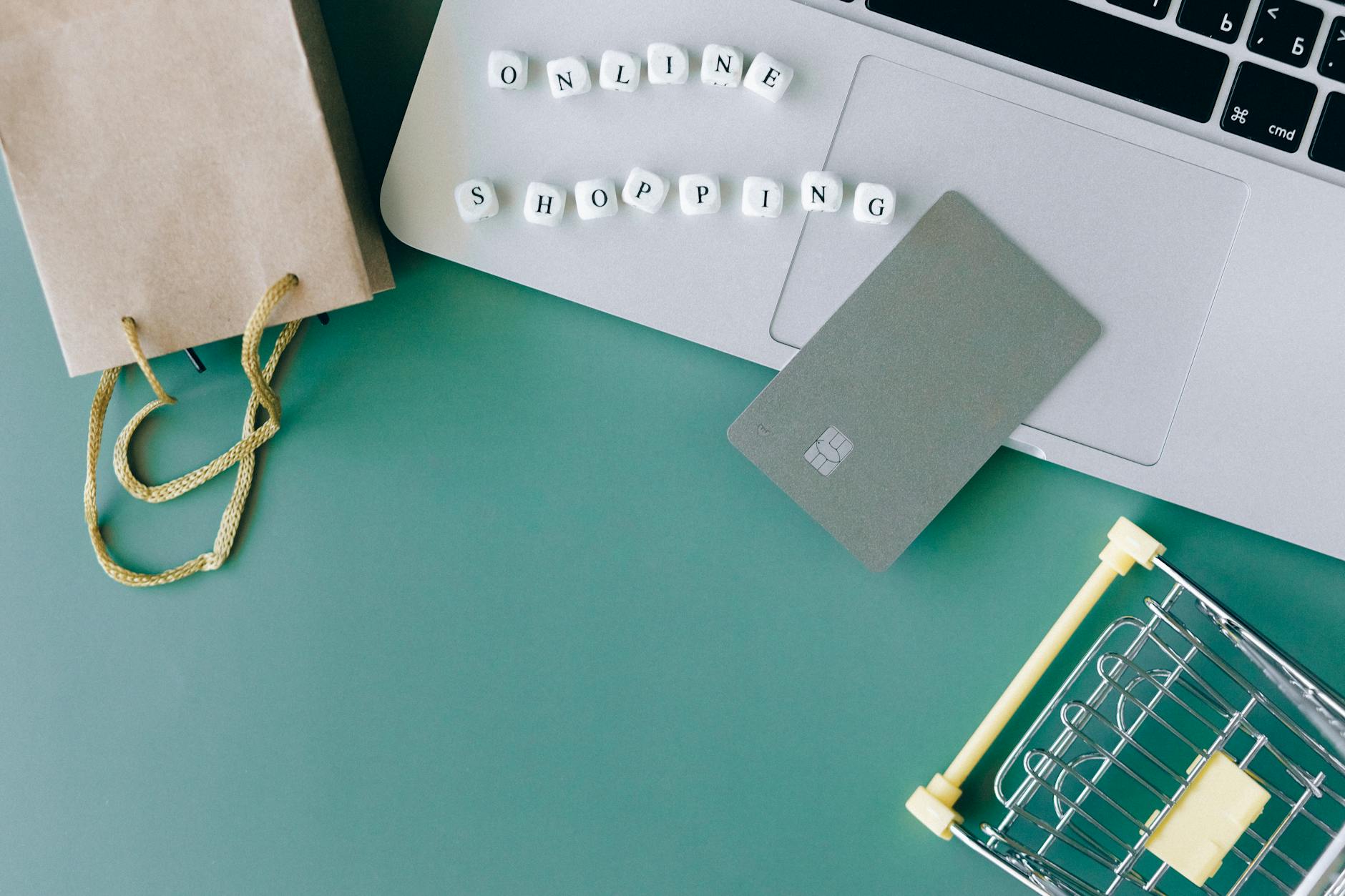 Laptop, karta płatnicza i mini wózek jako niezbędnik zakupów online