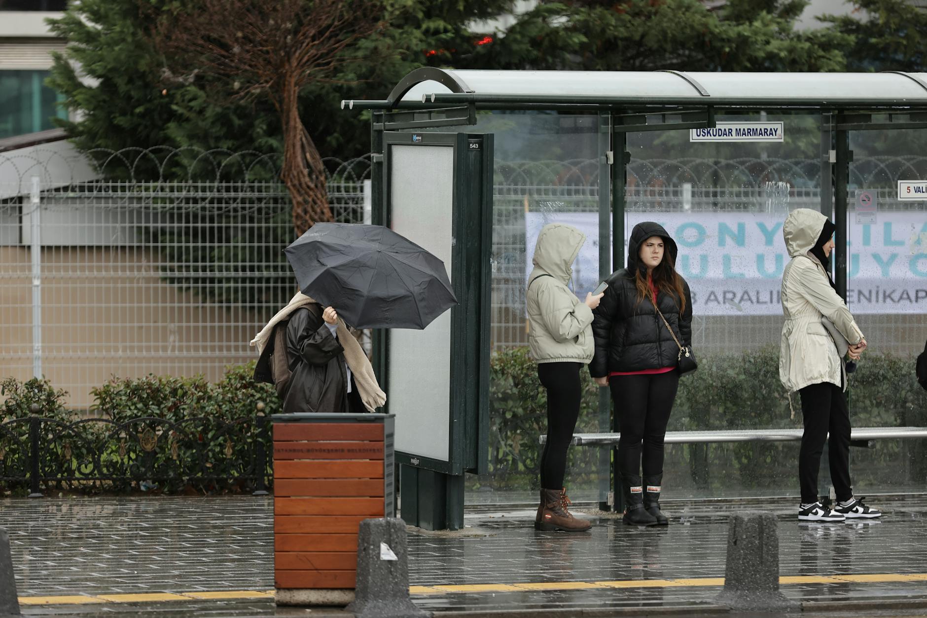 Pasażerowie z parasolami na deszczowym peronie stacji w Stambule