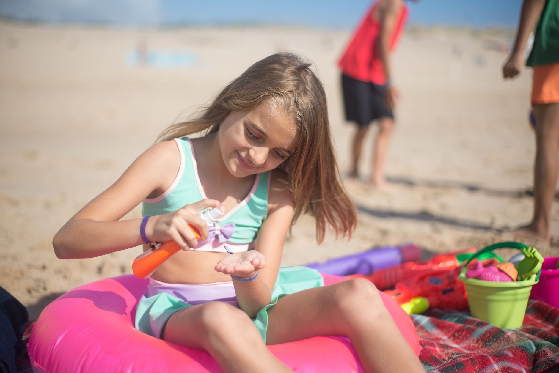 Dziewczynka nakłada krem z filtrem na plaży podczas słonecznych wakacji
