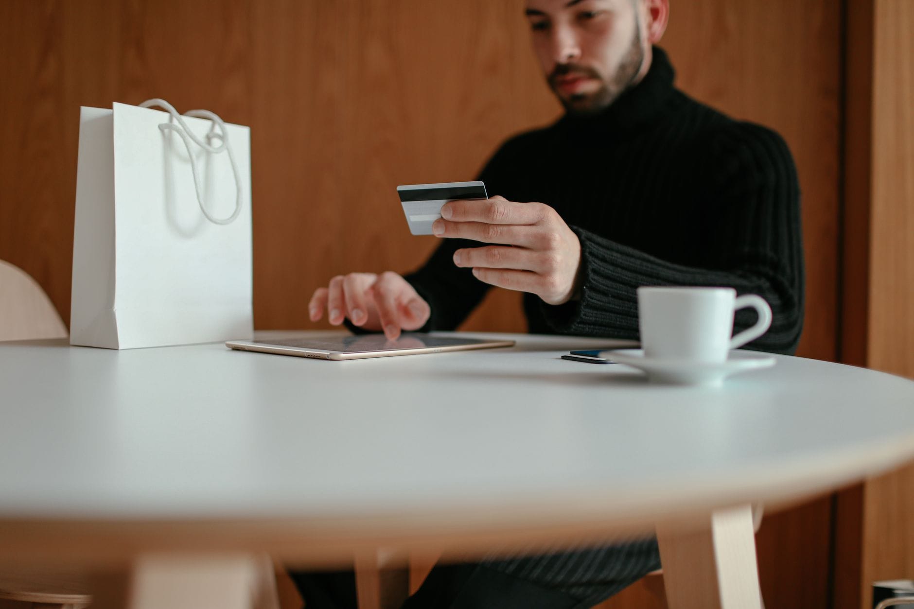 Mężczyzna płaci kartą za zakupy online na tablecie w kawiarni