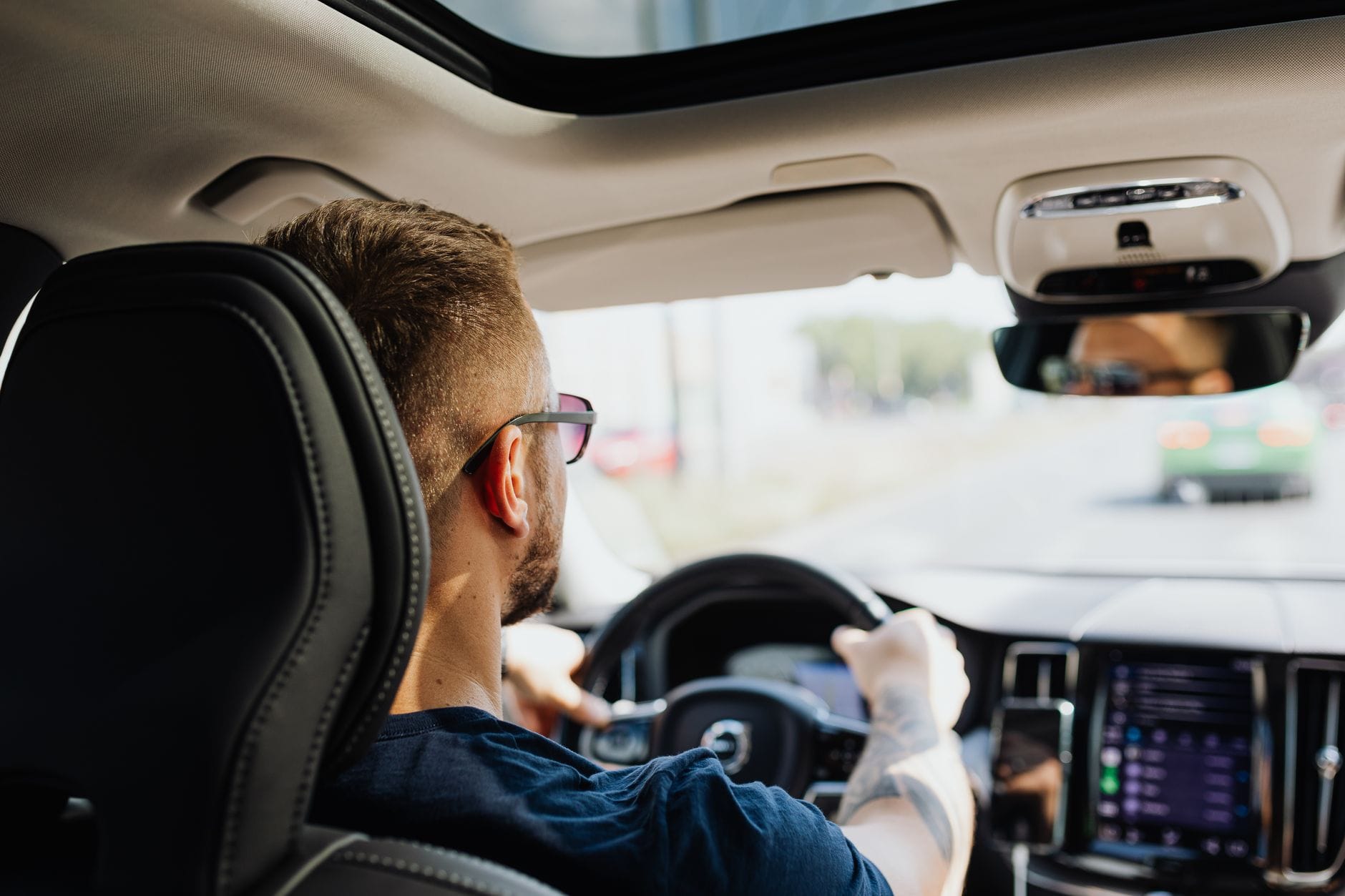 Mężczyzna prowadzi auto, widok od tyłu na kierownicę i kokpit