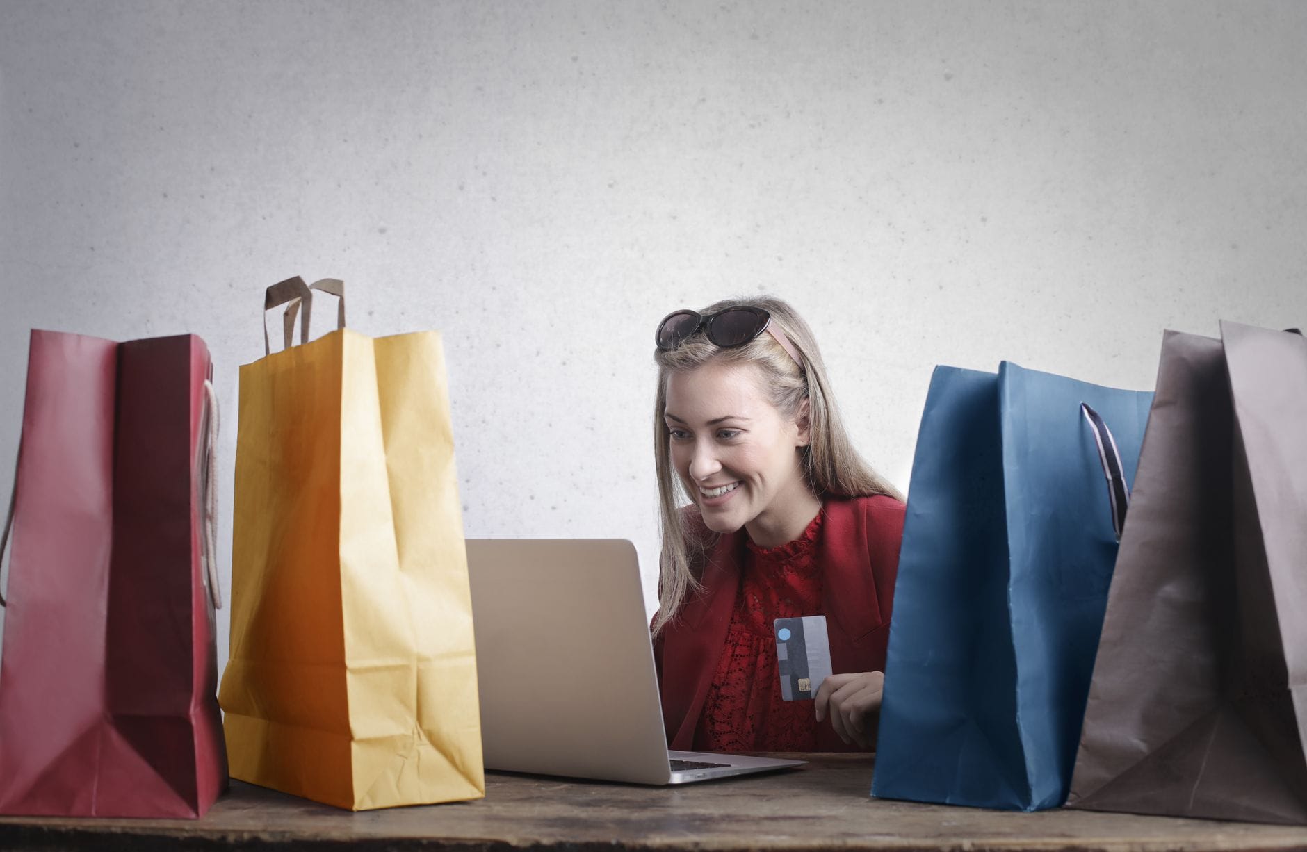 Uśmiechnięta kobieta z kartą kredytową robi zakupy online przy laptopie